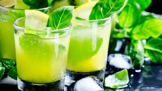 Lemonade with kiwi, green basil, grapefruit syrup and ice, black background, selective focus